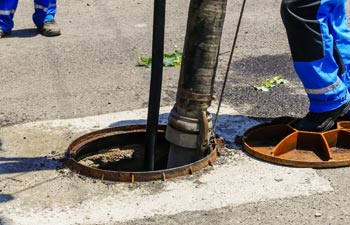 Workers cleaning the sewage at a residentual house on a bright sunny day