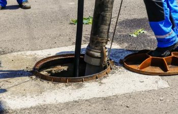 Workers cleaning the sewage at a residential house on a bright sunny day