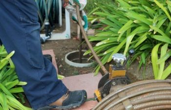 A plumber using a sewer snake to clean blockage in a sewer line