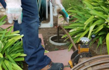 Sewer cleaning. A plumber uses a sewer snake to clean blockage in a sewer line