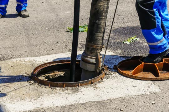 Workers cleaning the sewage at a residentual house on a bright sunny day