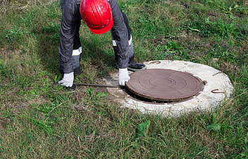 plumber opens a water well with a crowbar